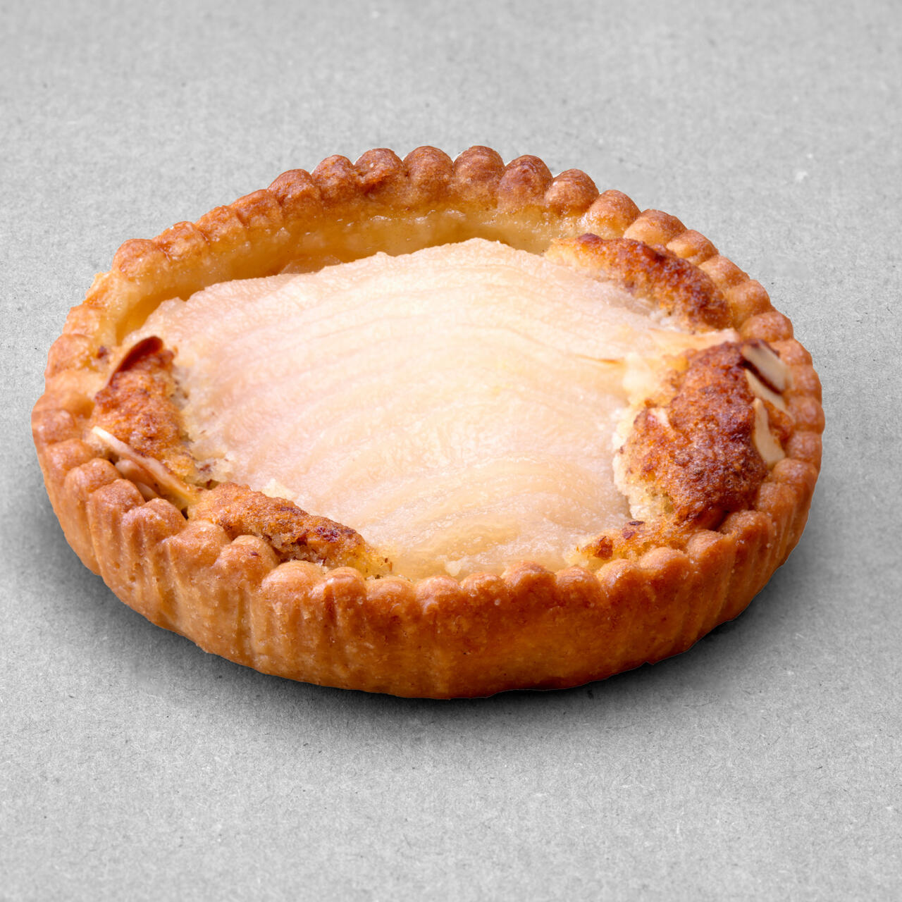 Tartelette aux poires et aux amandes posée sur un fond gris