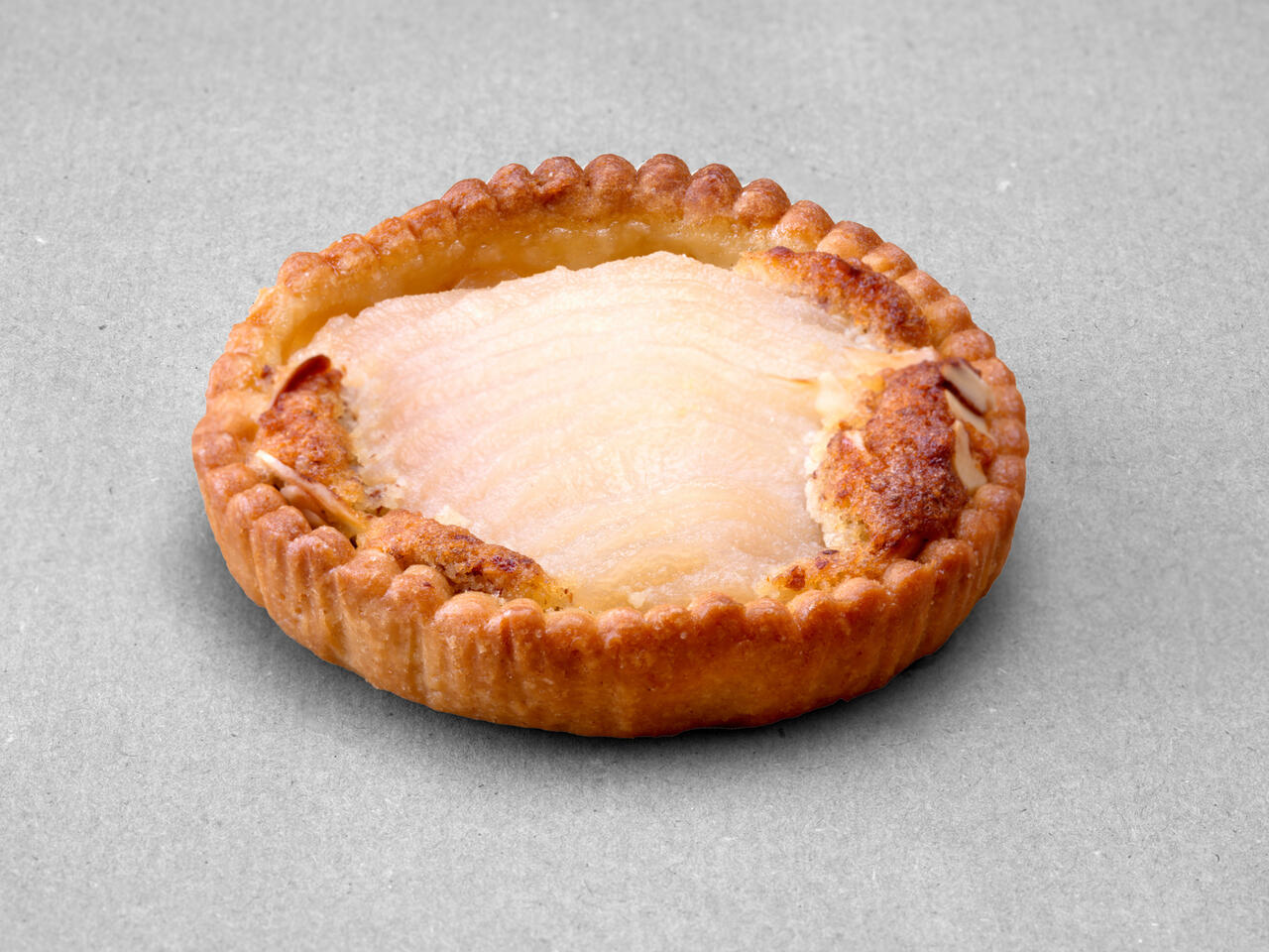 Tartelette aux poires et aux amandes posée sur un fond gris