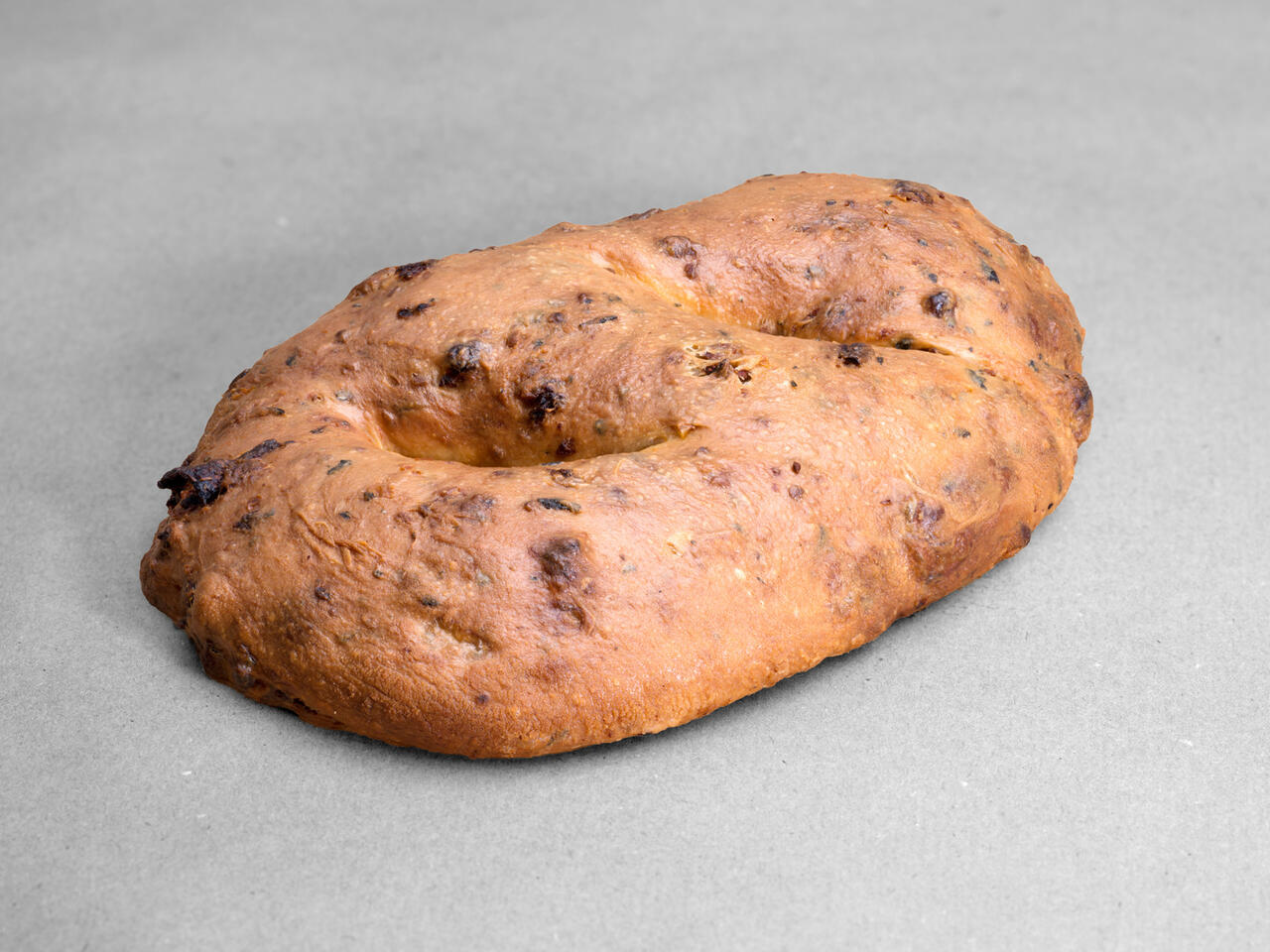Fougasse tomates séchées, ail et basilic posées sur un fond gris