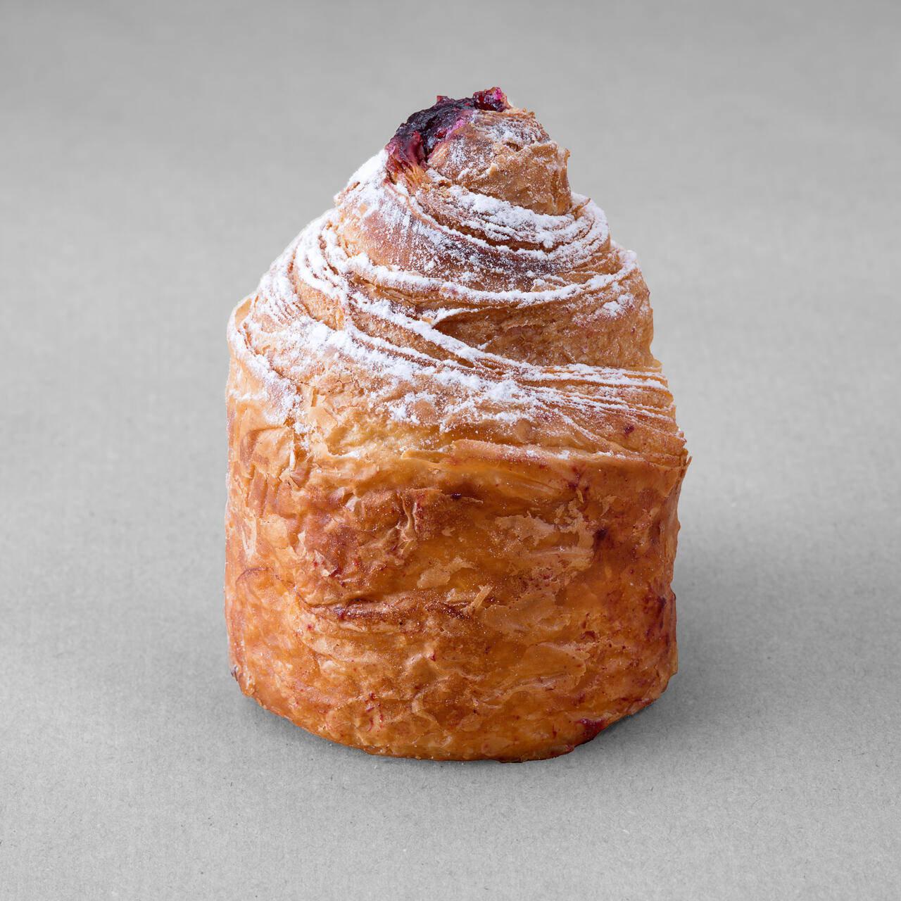 Cruffin aux myrtille posé sur un fond gris